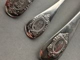 three spoons and a spoon rest on a table with silverware