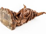 statue of a woman laying on a piece of wood on a white surface
