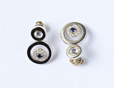 paire de boucles d'oreilles noires et blanches ornées de pierres bleues sur un fond blanc