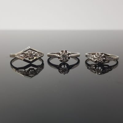three diamond rings on a black surface with a reflection
