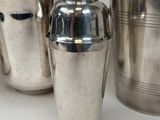 three silver cocktail shakers sitting next to each other on a white surface