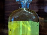 a bottle of liquid sitting on a table next to a bottle of liquid