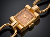une image représentant une montre en or avec une chaîne, posée sur un fond noir