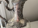 a silver pitcher sitting on a table with a tag on it