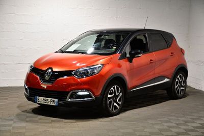 La voiture orange est garée dans le garage, sur le sol à damier.