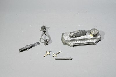 une petite boîte en argent contenant une clé, une bague et d'autres objets, posée sur une surface blanche
