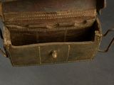 a brown leather box with a handle on a gray surface