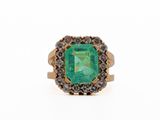 a close up of an emerald and diamond ring on a white background
