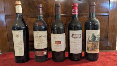several bottles of wine are lined up on a red table cloth