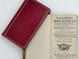 an old book sitting on top of a white table next to a red book