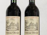 two bottles of red wine sitting on top of a wooden table