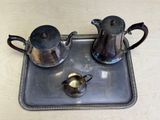 a silver tray with a tea pot and two cups on it