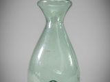 a green glass vase with a white top on a gray background