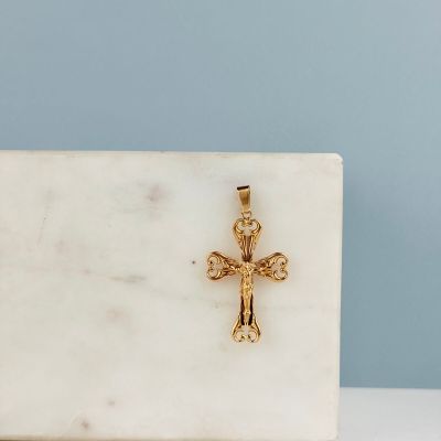 une croix plaquée or posée sur un bloc de marbre blanc, sur fond bleu