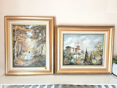 two paintings of a house and trees are hanging on a wall
