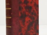 un vieux livre à la couverture rouge posé sur une table blanche
