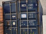 un homme debout à côté d'une pile de conteneurs d'expédition dans un entrepôt
