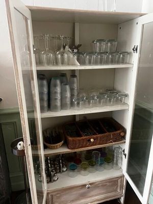 un placard sur lequel sont posés de nombreux verres, dans la cuisine