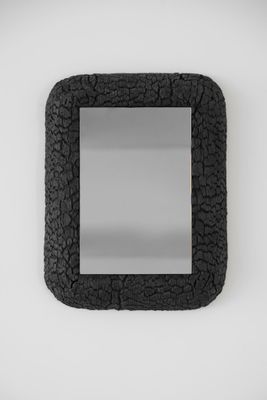 une image représentant un miroir au cadre noir accroché à un mur blanc