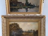 two framed paintings of a river scene with a church in the background