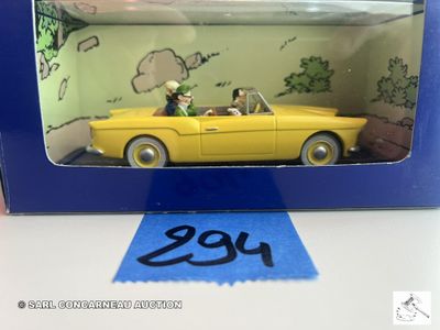 une petite voiture jaune avec deux personnes à bord, dans une boîte bleue