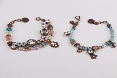 two bracelets with beads and charms on a white surface