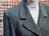 a suit on a mannequin stand in front of a woven wall