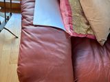 a laptop sitting on top of a brown leather couch