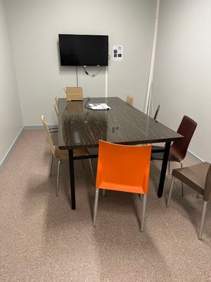 des tables et des chaises dans une salle de réunion, avec une télévision à écran plat accrochée au mur