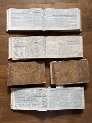several old books are stacked on top of each other on a wooden floor