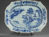 blue and white plate with a landscape scene on it on a stand