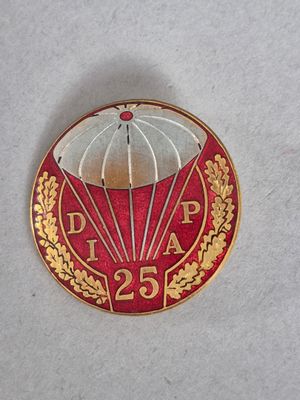 un pin's rouge et doré sur lequel est représenté un parachute
