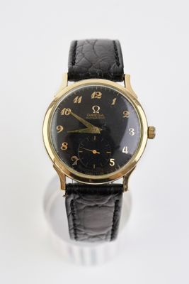 une image représentant une montre-bracelet noire et dorée posée sur une surface blanche