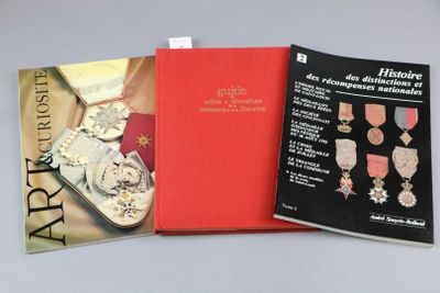 trois livres posés sur une table, dont l'un a une couverture rouge et une médaille d'or