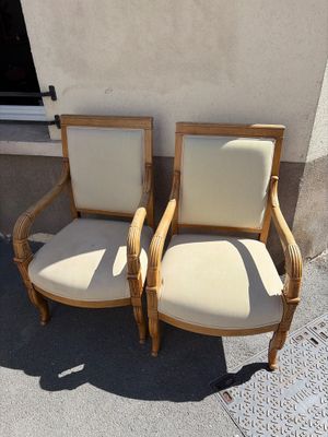 two wooden chairs sitting next to each other in front of a building