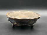 an old metal bowl sitting on top of a black table