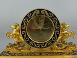 a gold clock with black and gold decorations on it