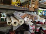 many rolls of paper and cans of paint on a shelf