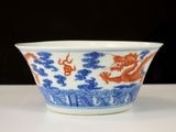 a blue and white bowl with a red dragon on it