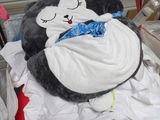 a stuffed penguin that is laying on a pile of clothes