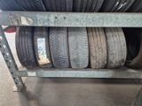 Plusieurs pneus sont empilés sur un support métallique dans un garage.