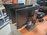 three computer monitors sitting on a desk next to each other