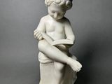 marble statue of a boy sitting on a stool with his legs crossed