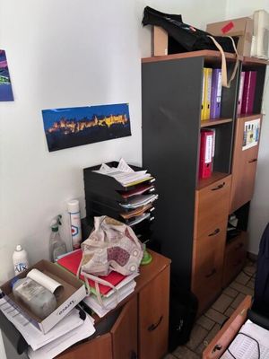 une photo d'une pièce encombrée avec un bureau et une bibliothèque