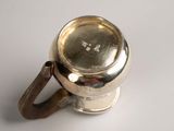 a silver cup with a handle on a white surface