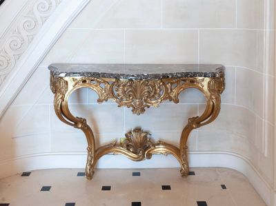 a marble top table with a gold frame and a black and white checkered floor