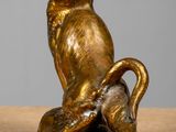 a gold statue of a cat sitting on a tree branch