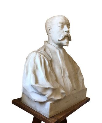 statue of a man with a mustache sitting on top of a wooden stand