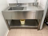 a stainless steel sink and a bucket on the floor