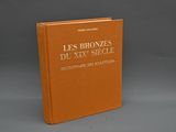 un livre orange posé sur une table près d'un mur gris